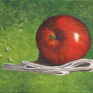 roter Apfel auf schwebendem Tuch mit Wassertropfen